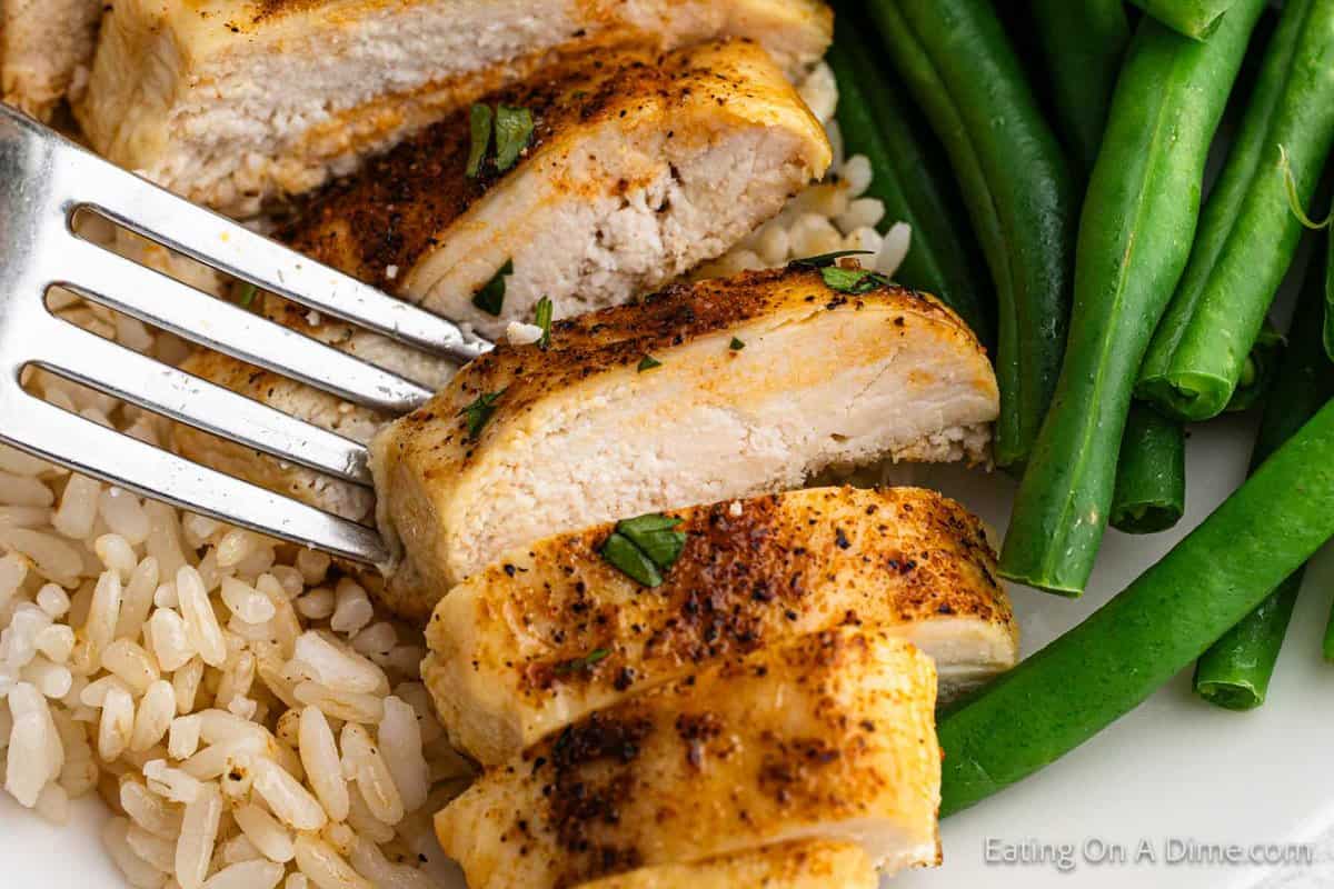 Slice chicken breast on a plate with rice and green beans 