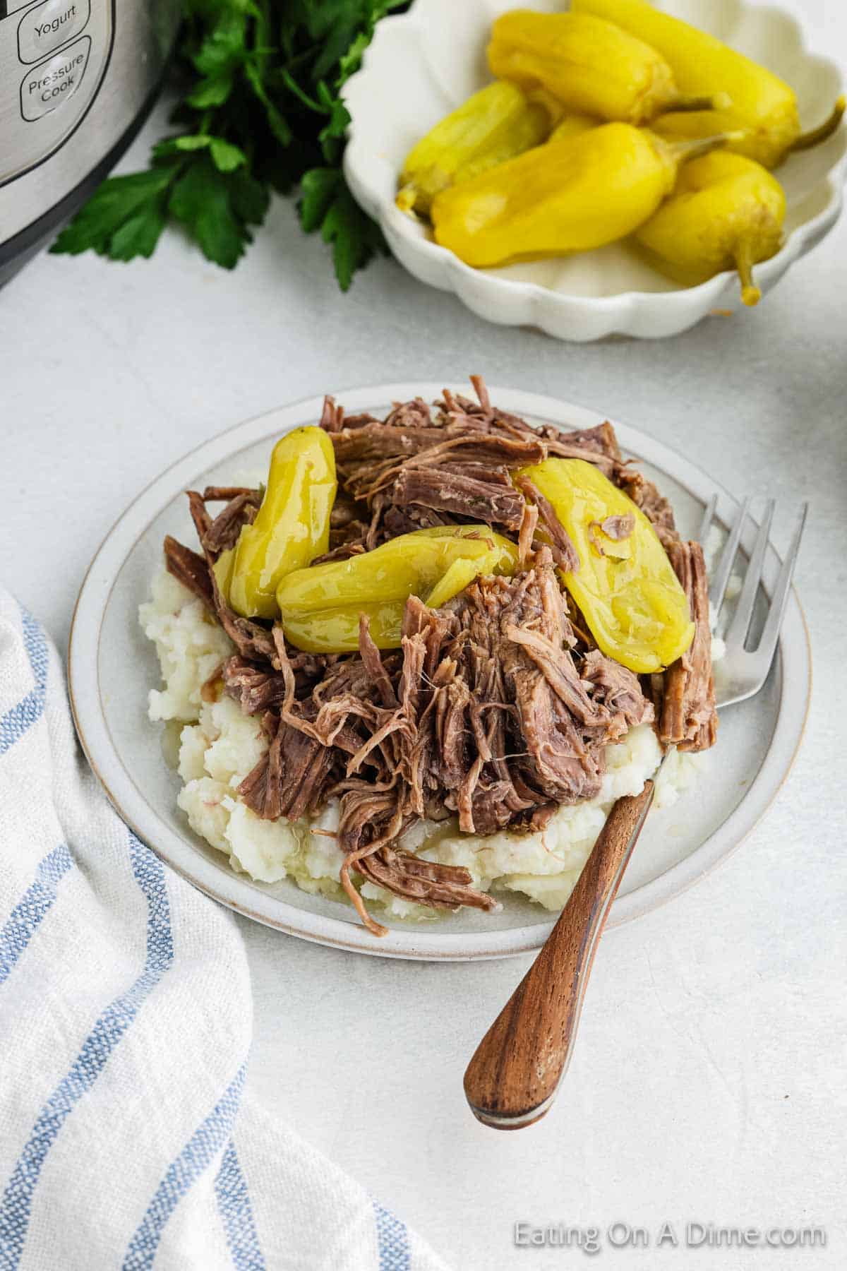 Shredded Roast over mashed potatoes with Pepperoncini Peppers with bowl of Pepperoncini Peppers on the side