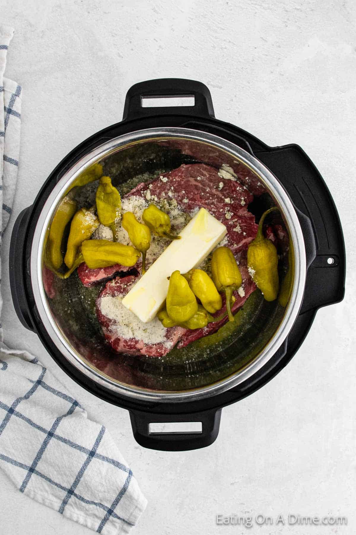 Topping the roast with Pepperoncini Peppers and a stick of butter in the instant pot