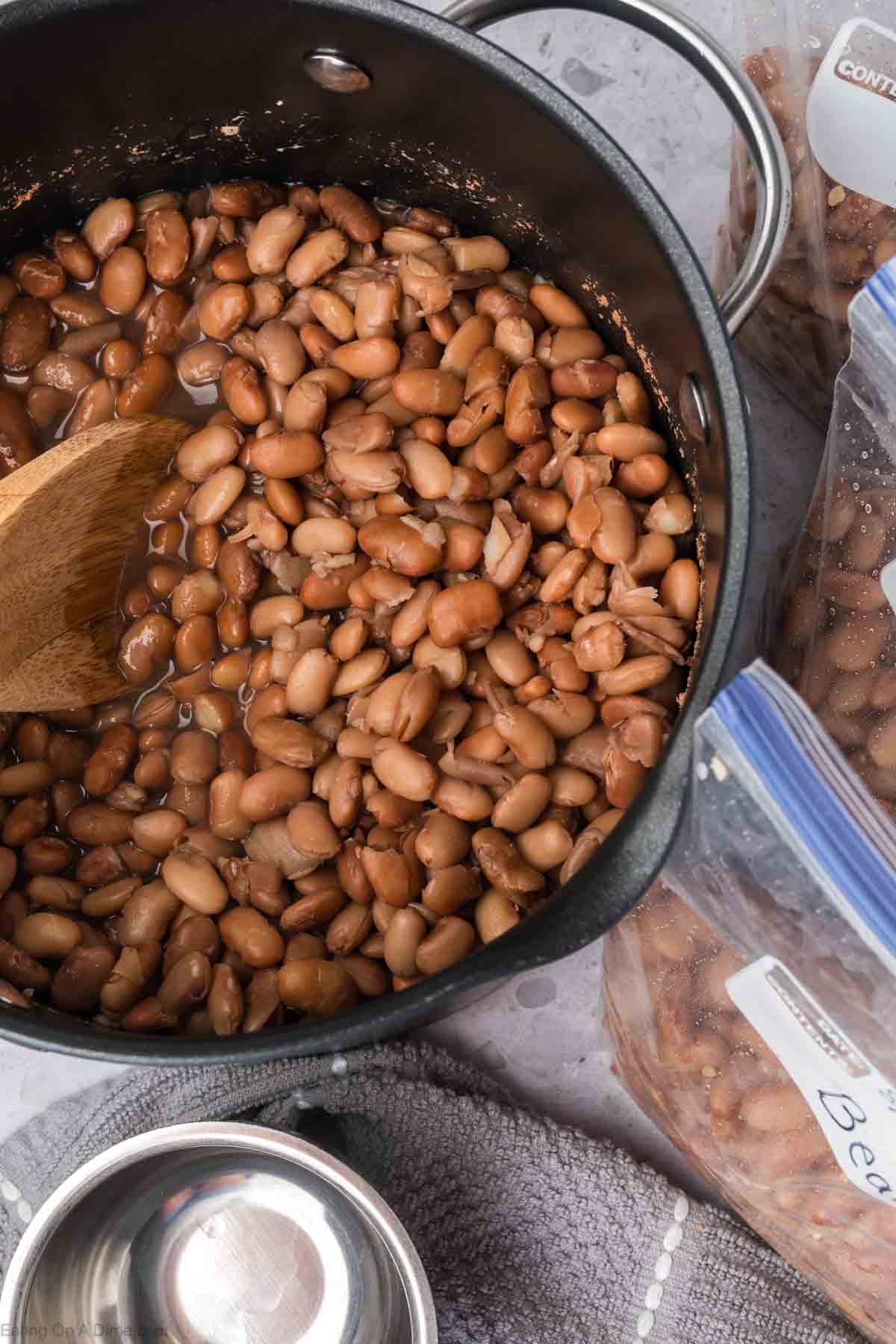 Cooked Brown Beans in a large pot with a wooden spoon