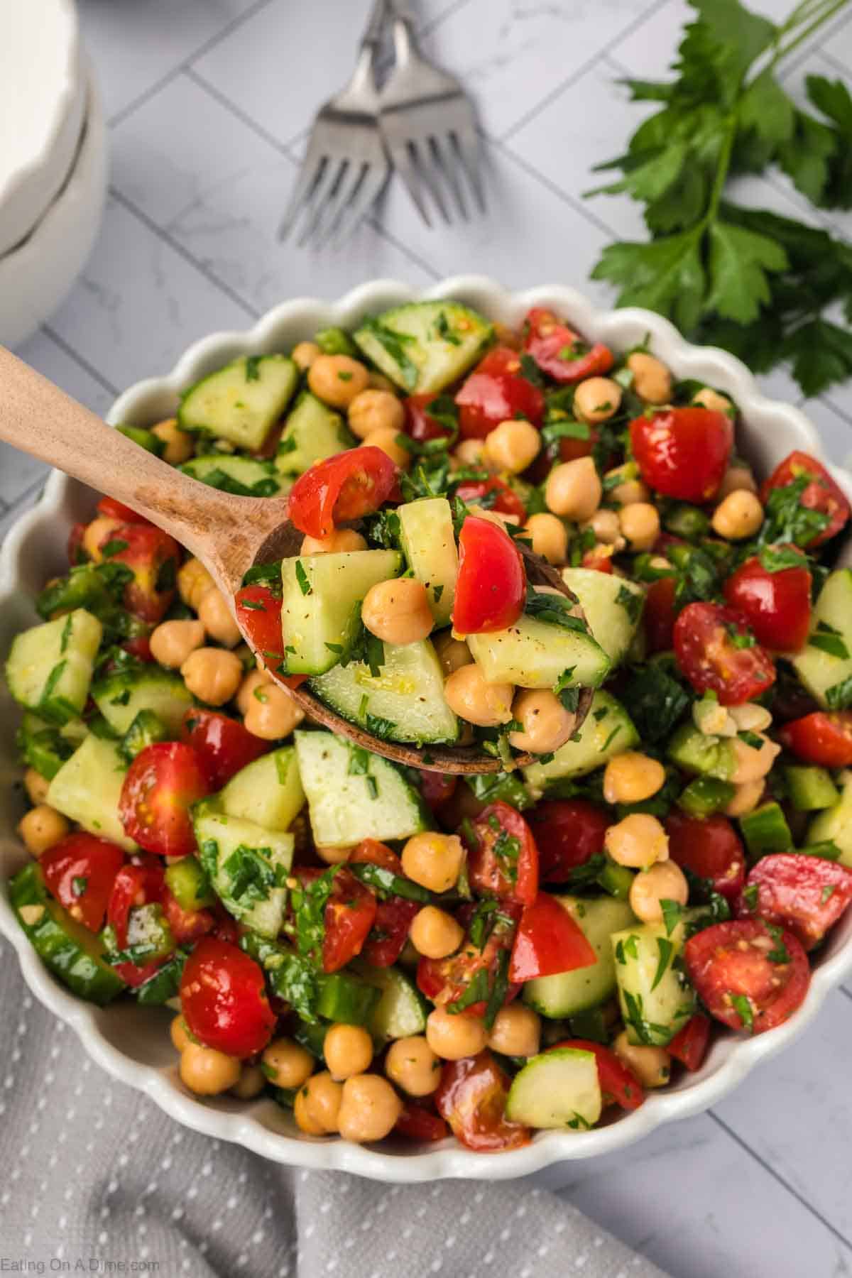 Chickpea salad in a bowl with a serving on a wooden spoon