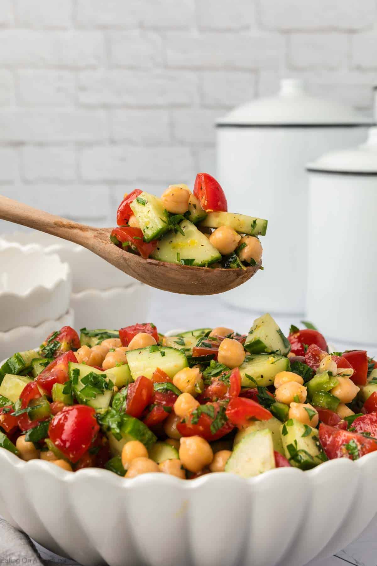 Chickpea salad in a bowl with a serving on a wooden spoon