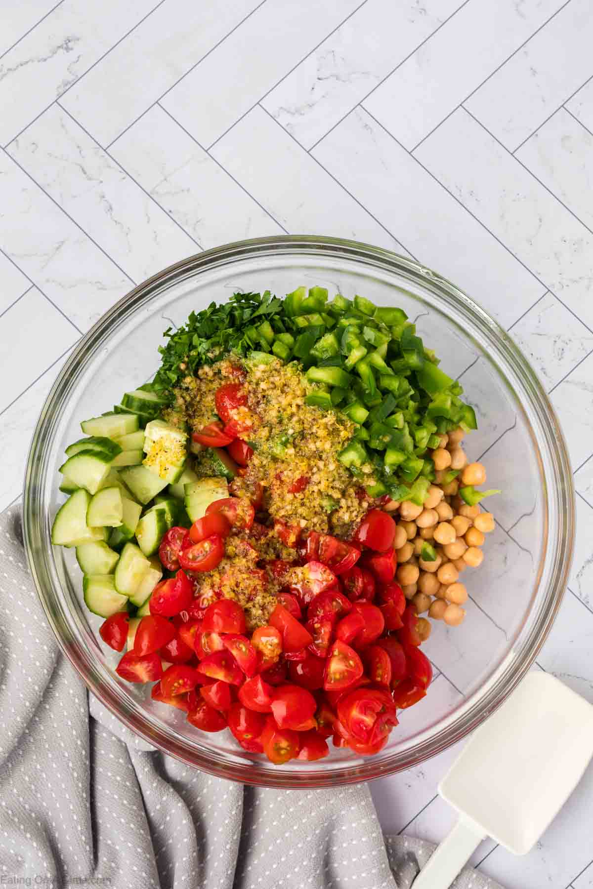 Chopped cherry tomatoes, diced cucumbers, bell peppers, parsley, chickpea topped with dressing in a bowl