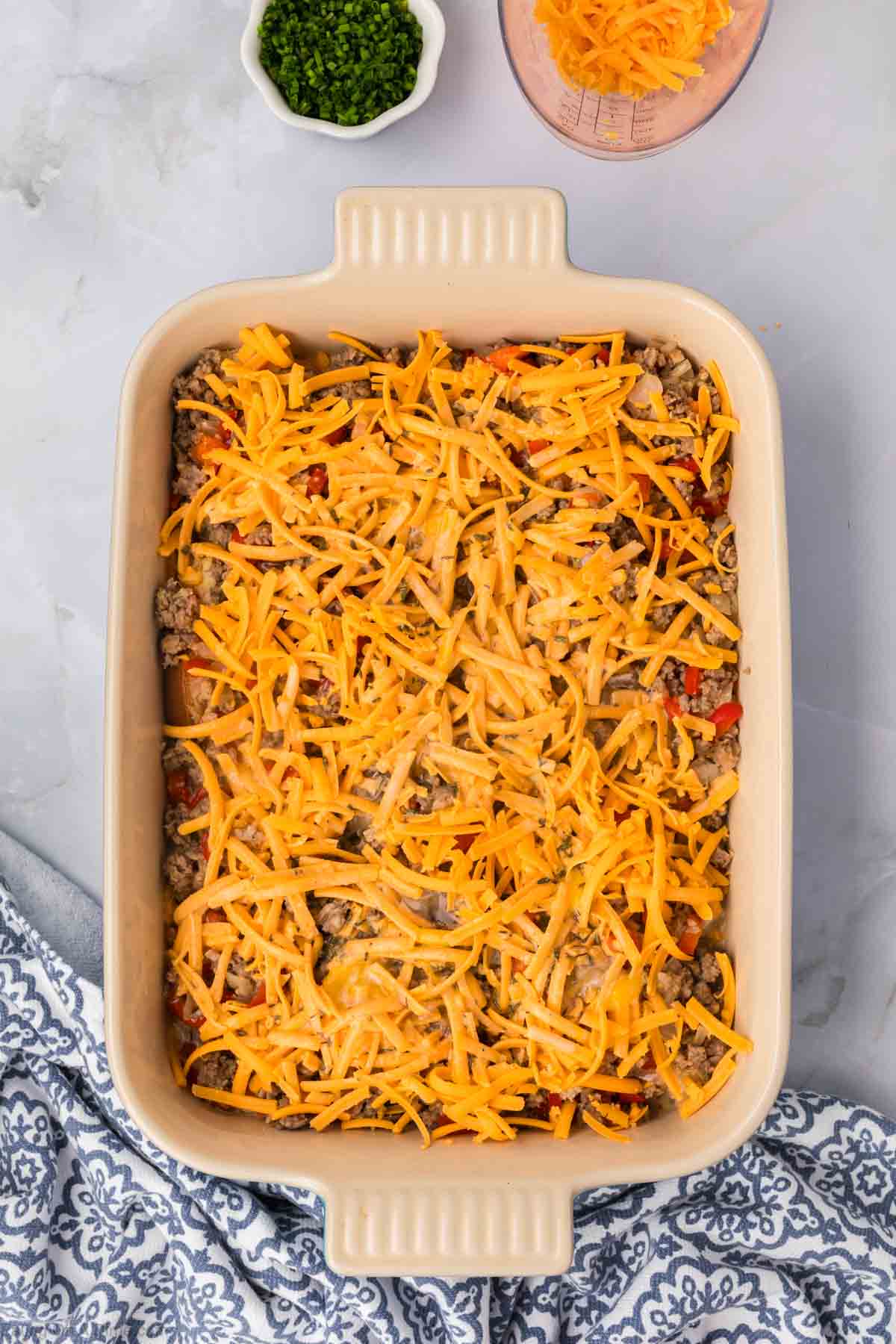 Pouring the egg mixture over the sausage and cheese mixture in the baking dish