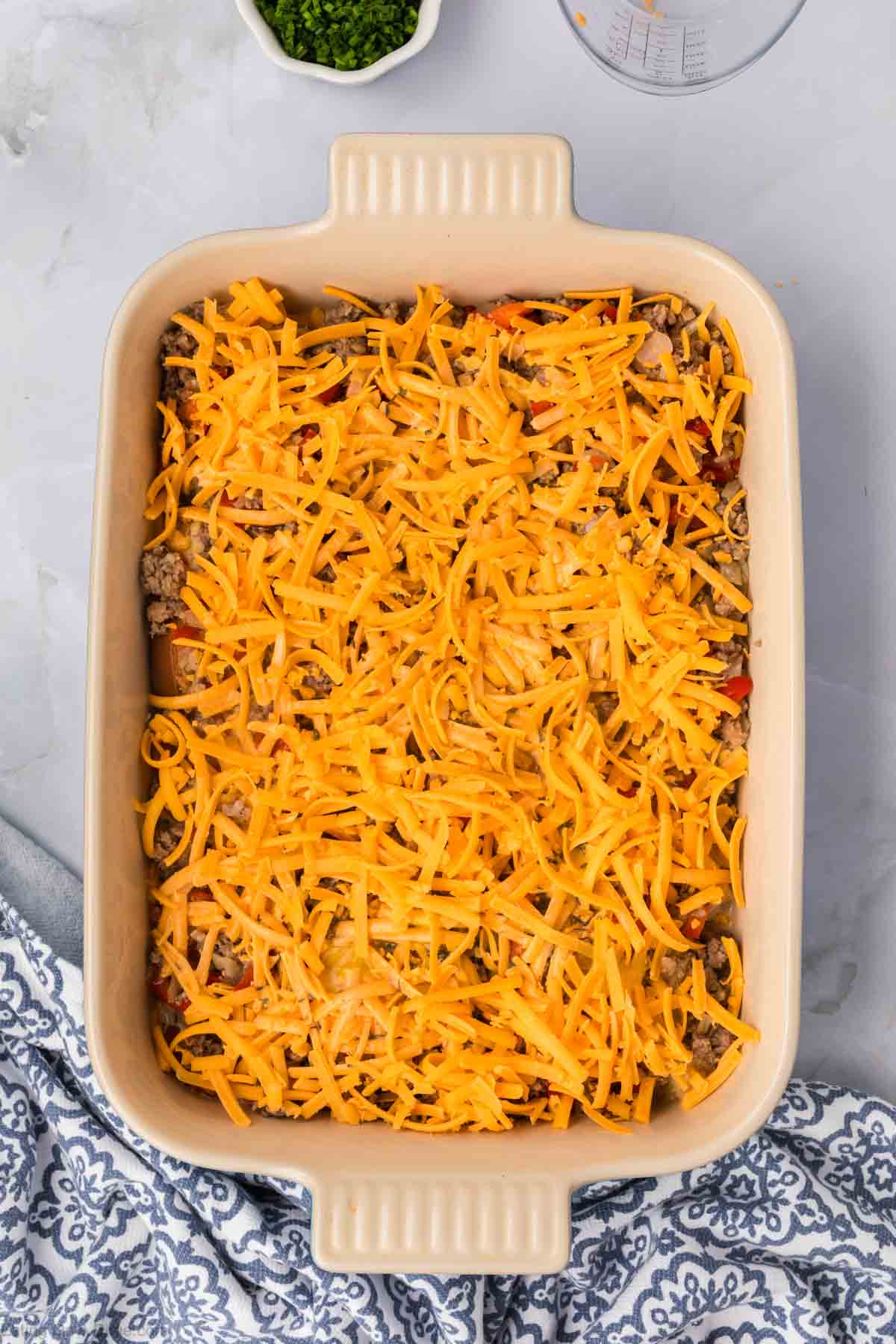 Shredded cheese on sausage mixture in a baking dish