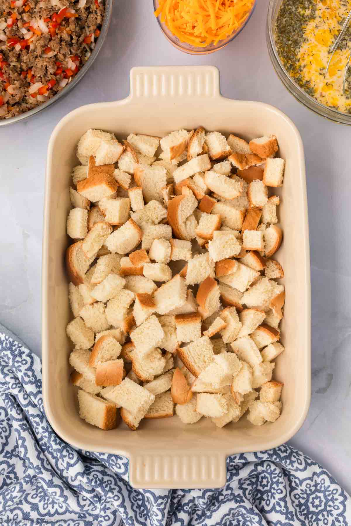 Layering the cubed bread in a baking dish