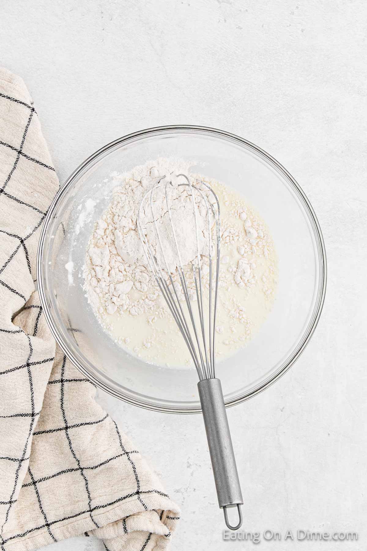 Flour and milk mixed together in a bowl with a whisk