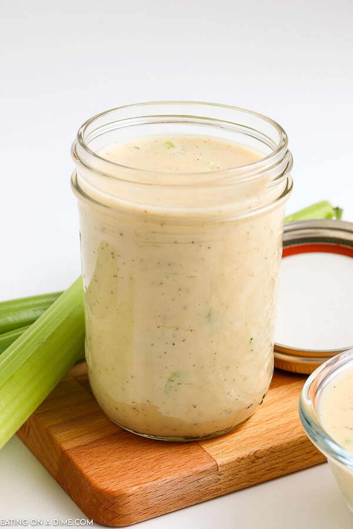 Cream of celery soup in a mason jar on a small board with a side of celery stalks