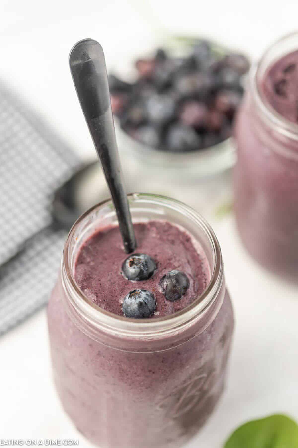 A Blueberry Spinach Smoothie with a spoon in the middle of it.  