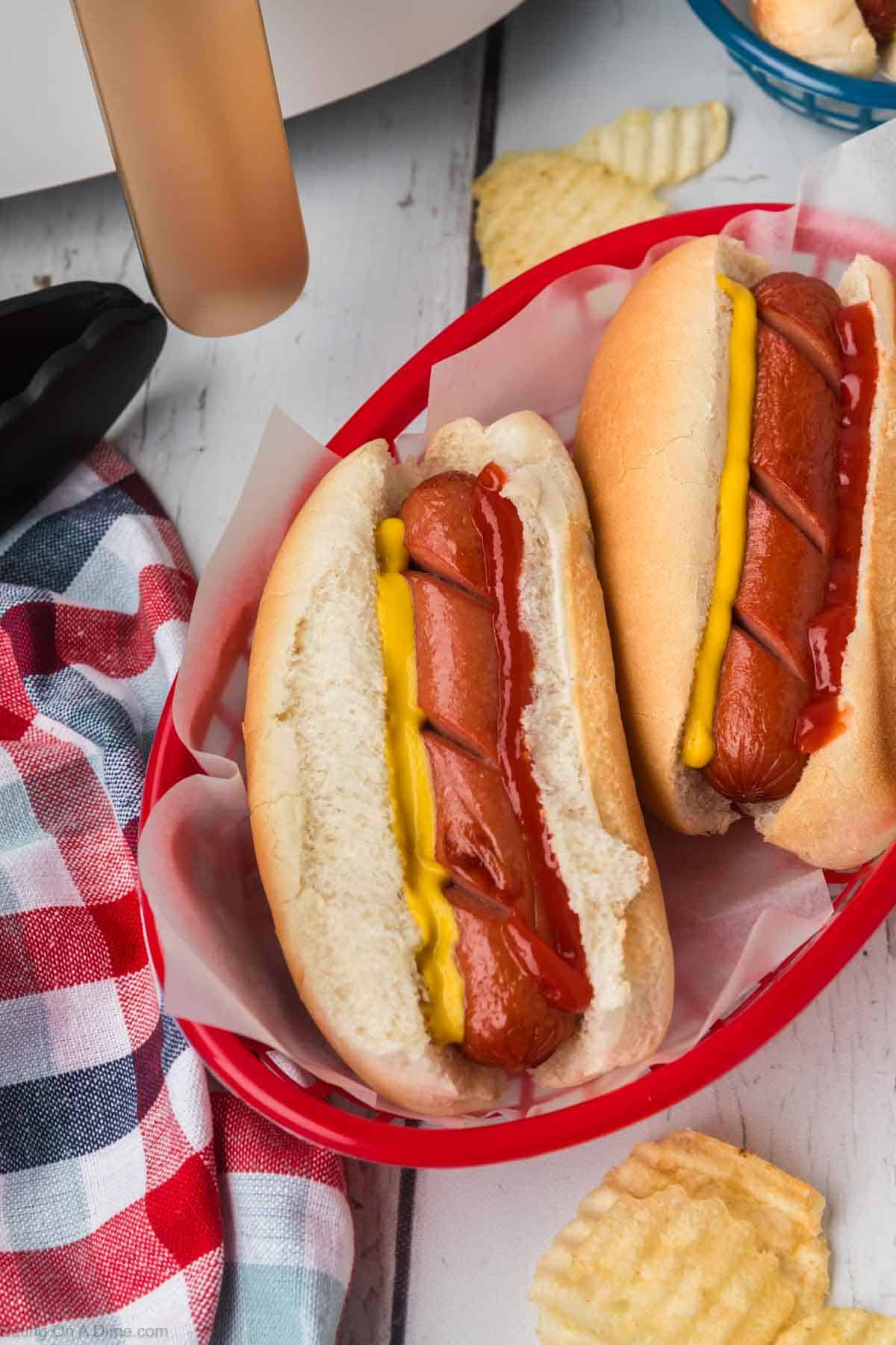 Hot Dogs in a red basket lined with parchment paper. The hot dogs are topped with mustard and ketchup