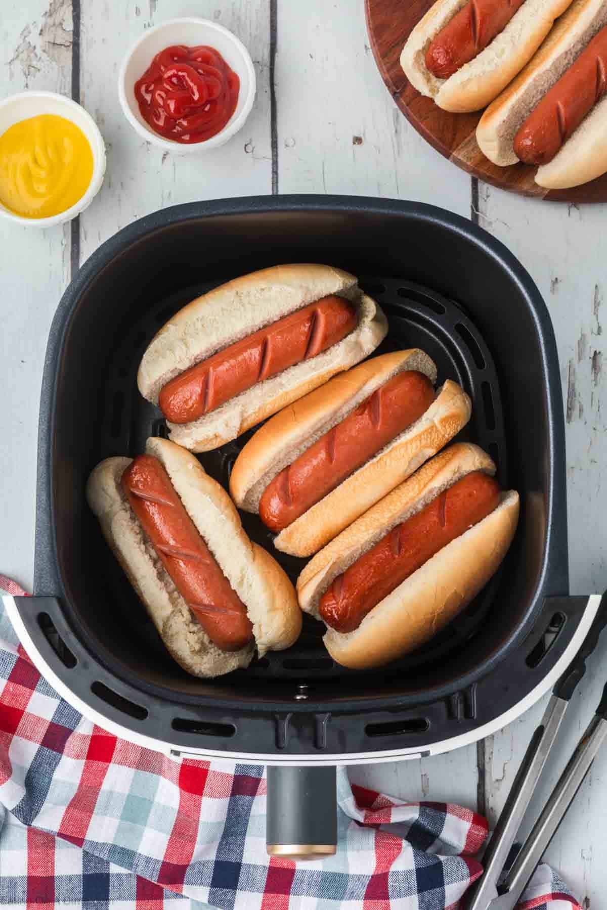 Hot dogs in hot dog buns in an air fryer basket