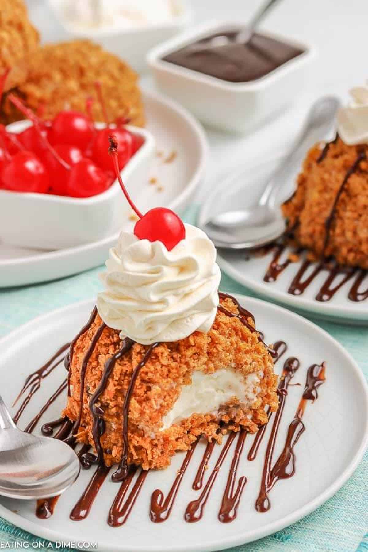 Fried Ice Cream on a white plate topped with whipped cream and a cherry. 