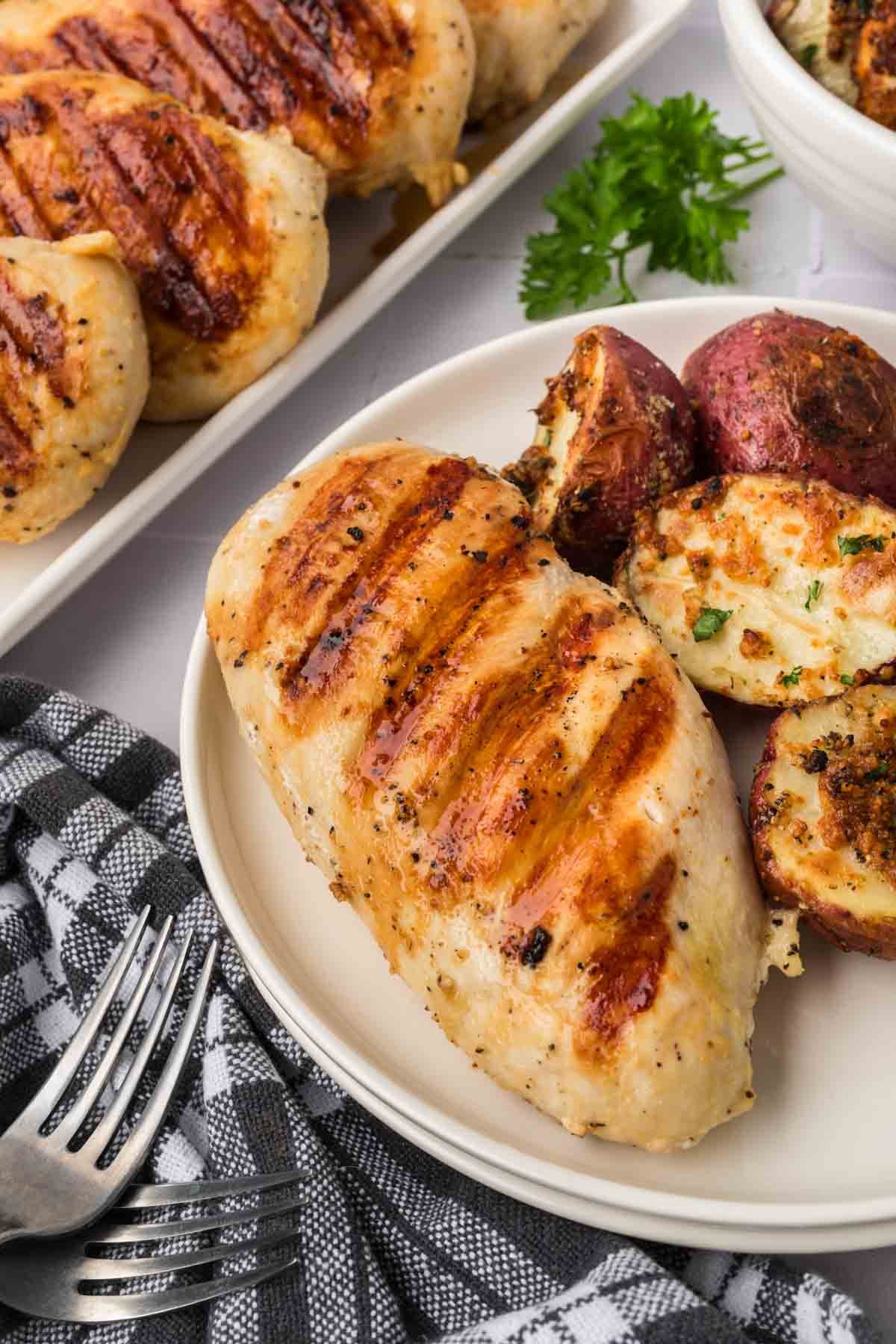 Grilled chicken breast on a plate with a side of roasted red potatoes