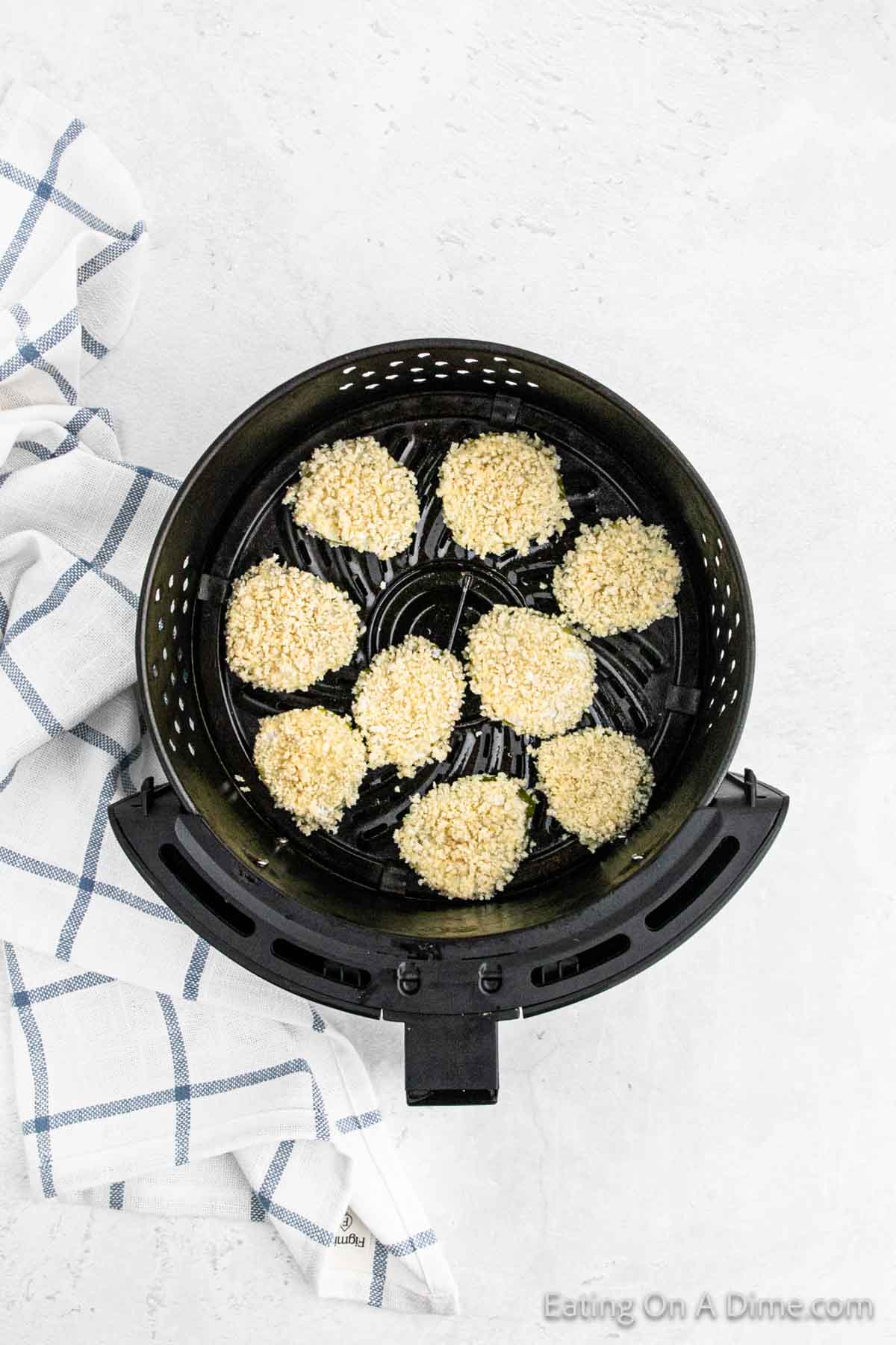 Placing the breaded pickles in the air fryer basket