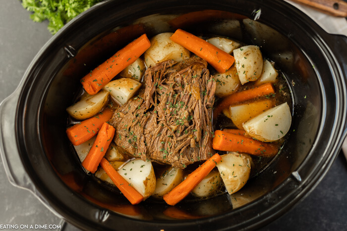 crockpot of cooked roast, carrots and potatoes