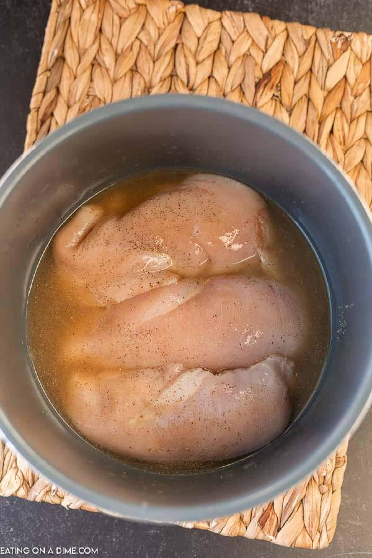 photo of raw chicken and broth in instant pot.