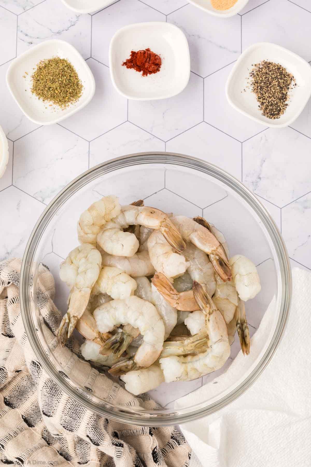 Shrimp in a bowl with bowls of spices on the side