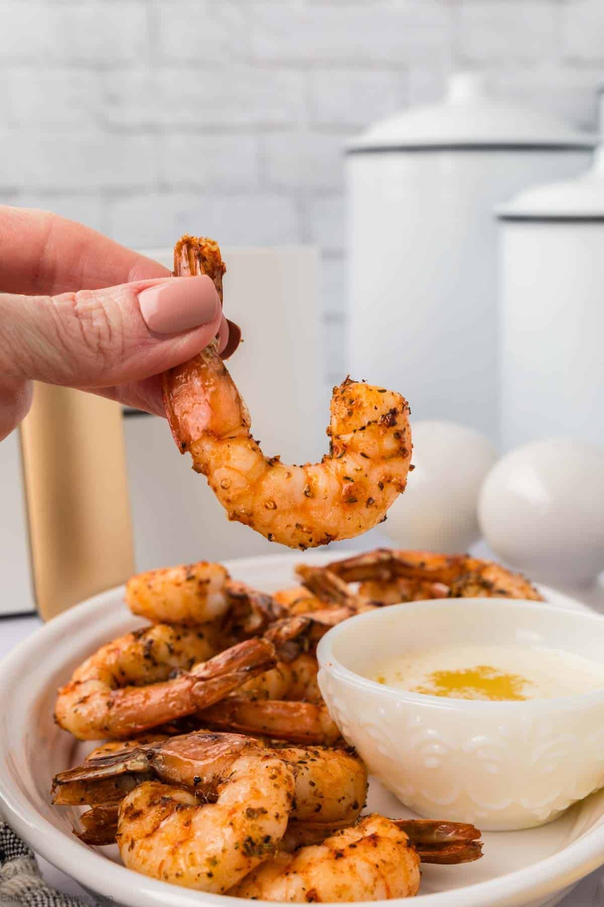 Air Fryer shrimp on a platter with a shrimp being held