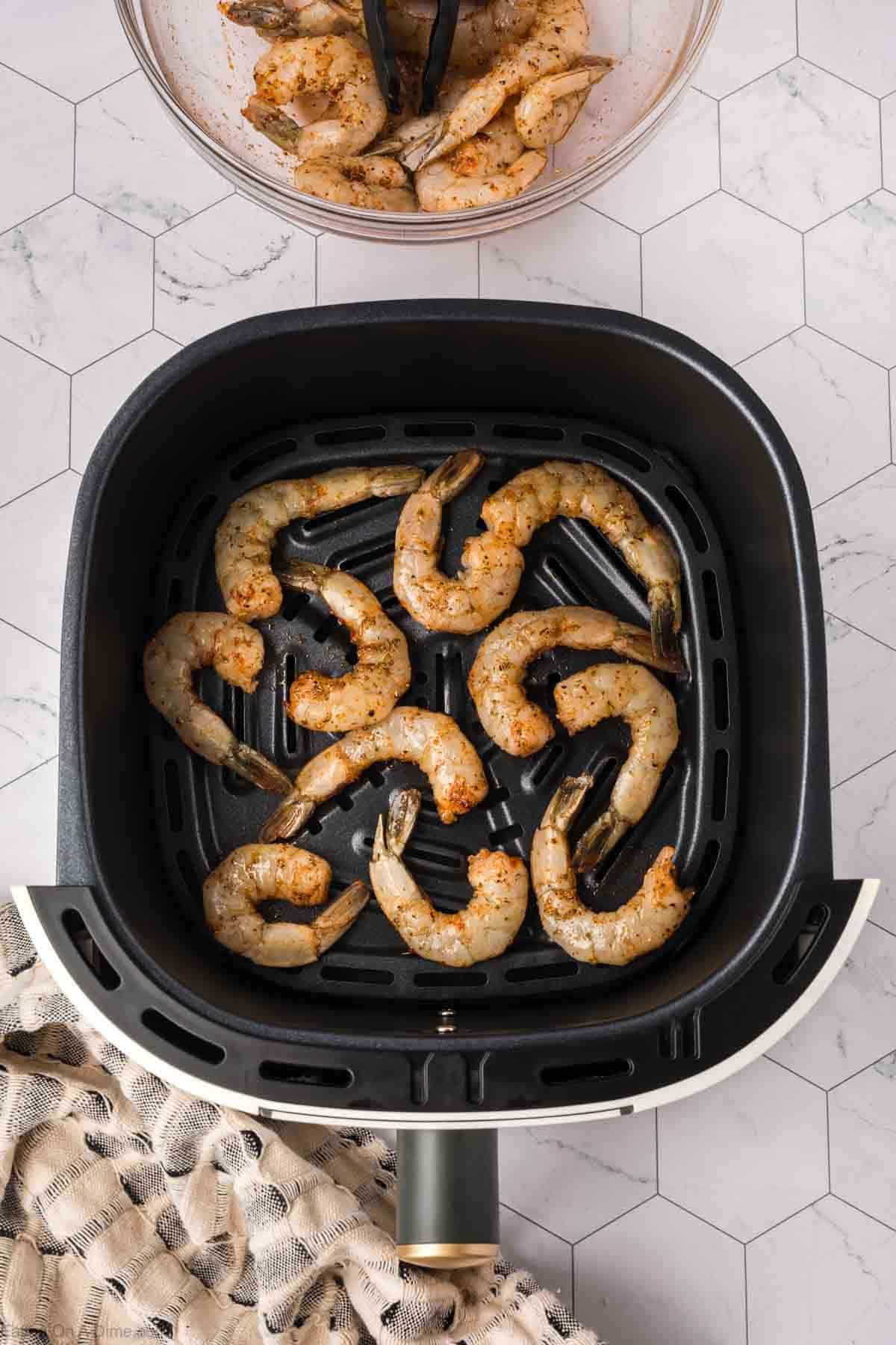 Seasoned uncooked shrimp in the air fryer basket