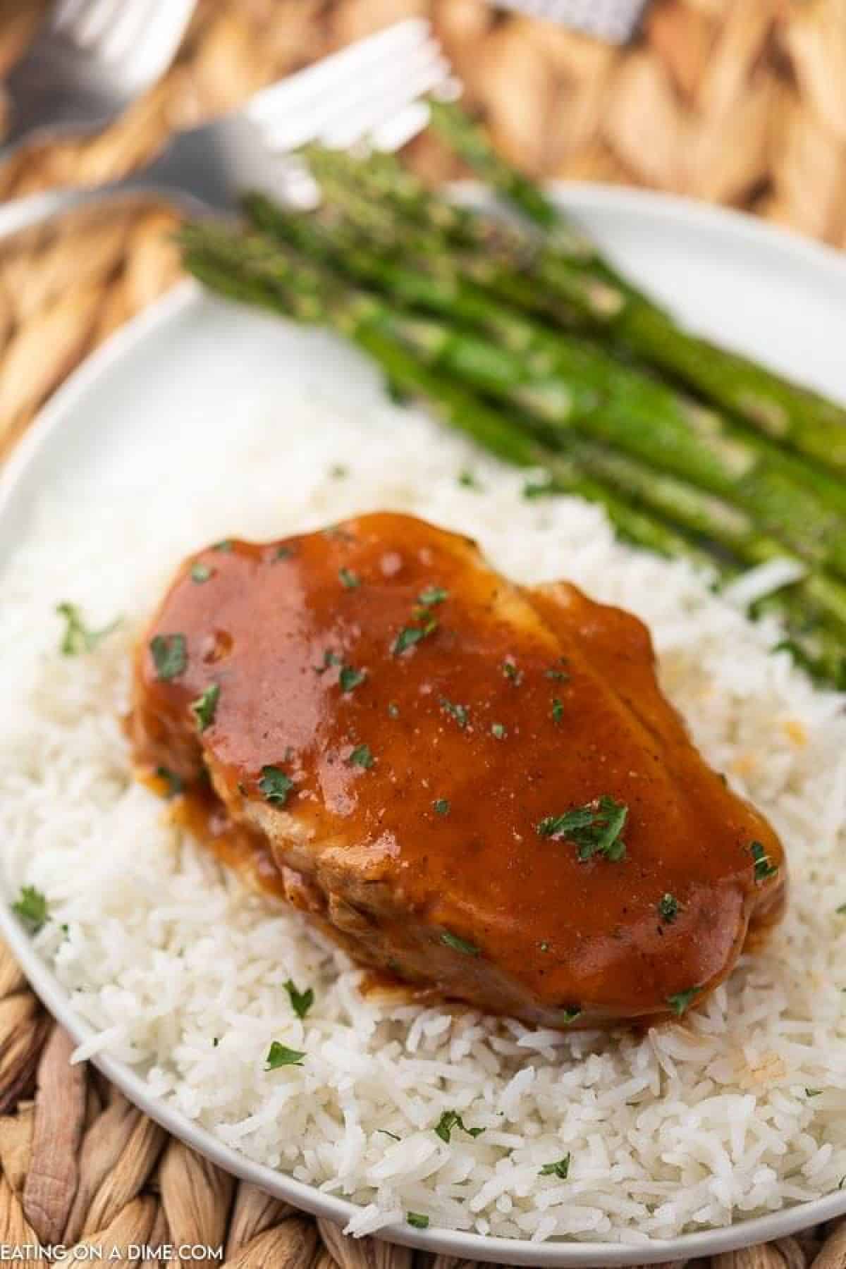 white plate with asparagus, rice and pork chop