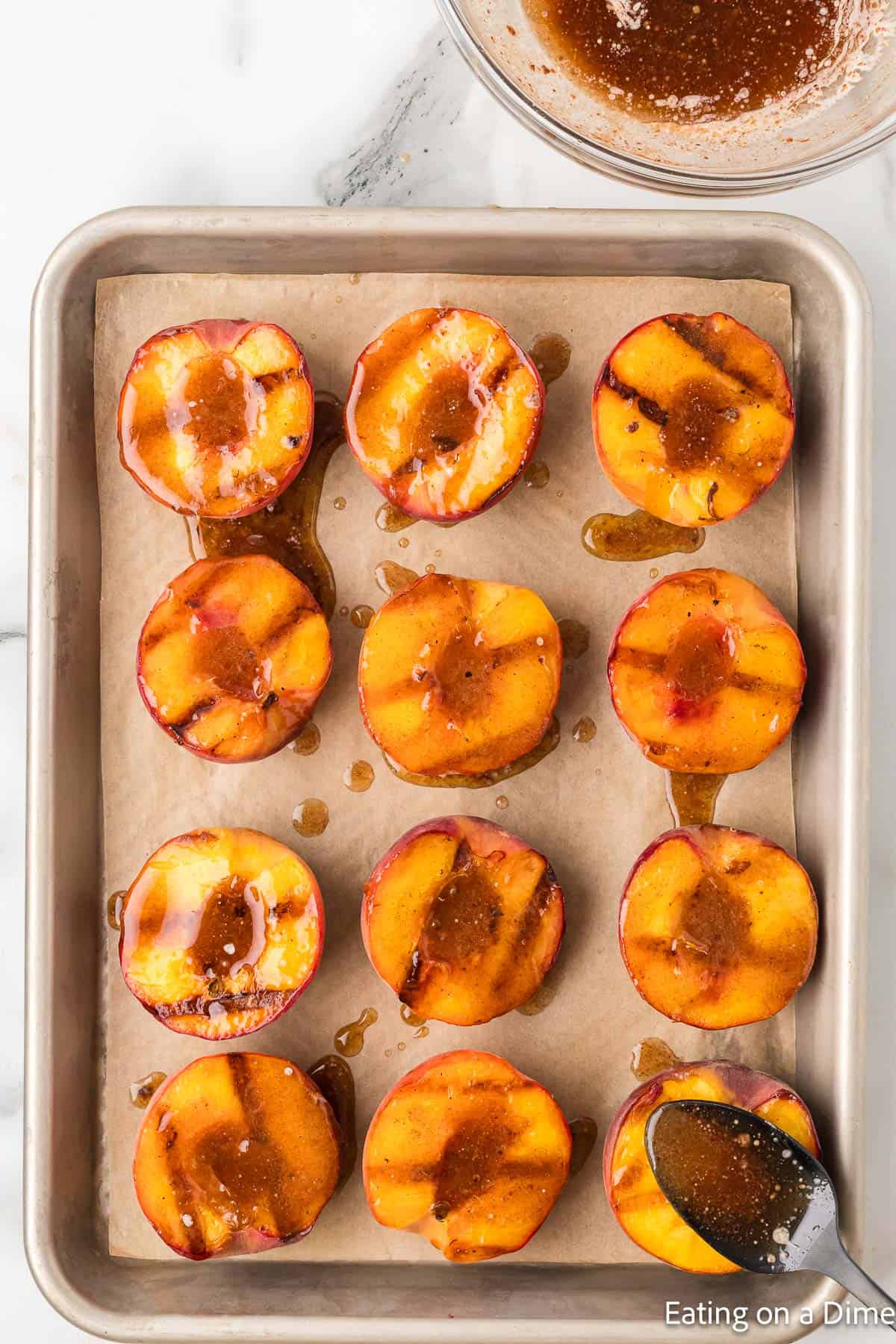 Topping the grilled peaches on a cutting board topped with melted butter mixture