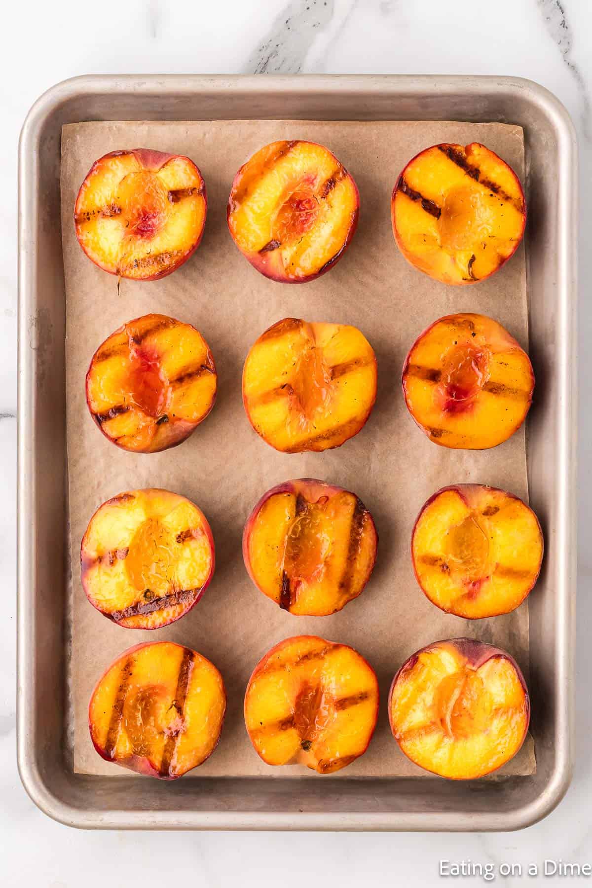 Slice grilled peach on a cutting board lined with parchment paper