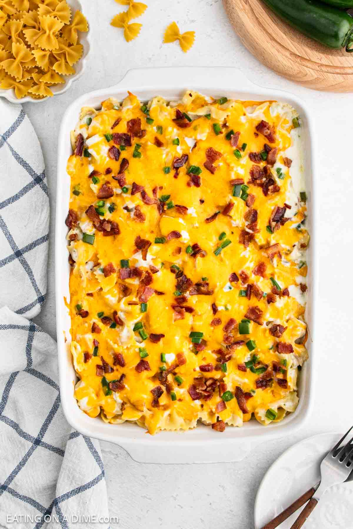 Jalapeno Popper Chicken Casserole in a baking dish topped with melted cheese, chopped bacon and chopped jalapeno