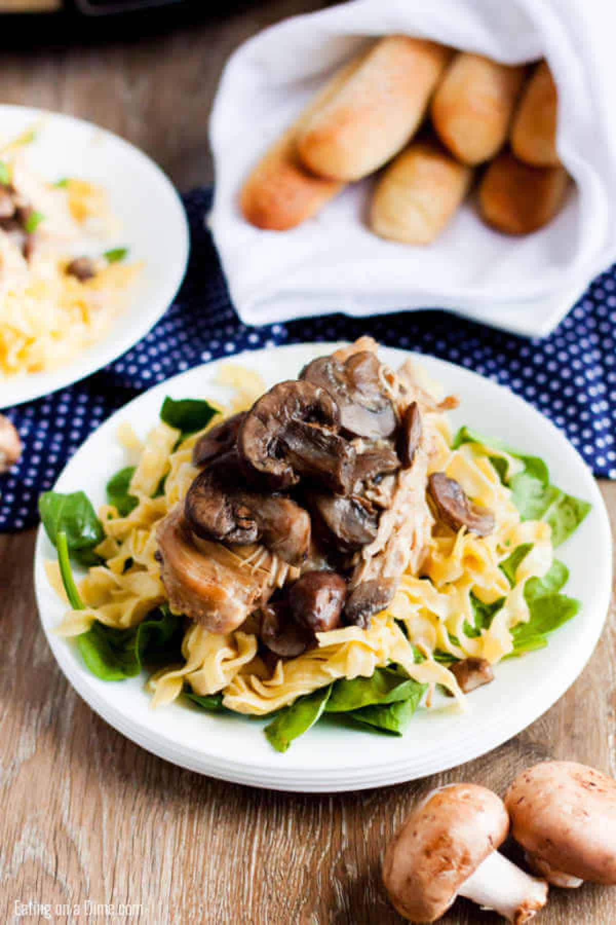 plate of chicken marsala with pasta and breadsticks