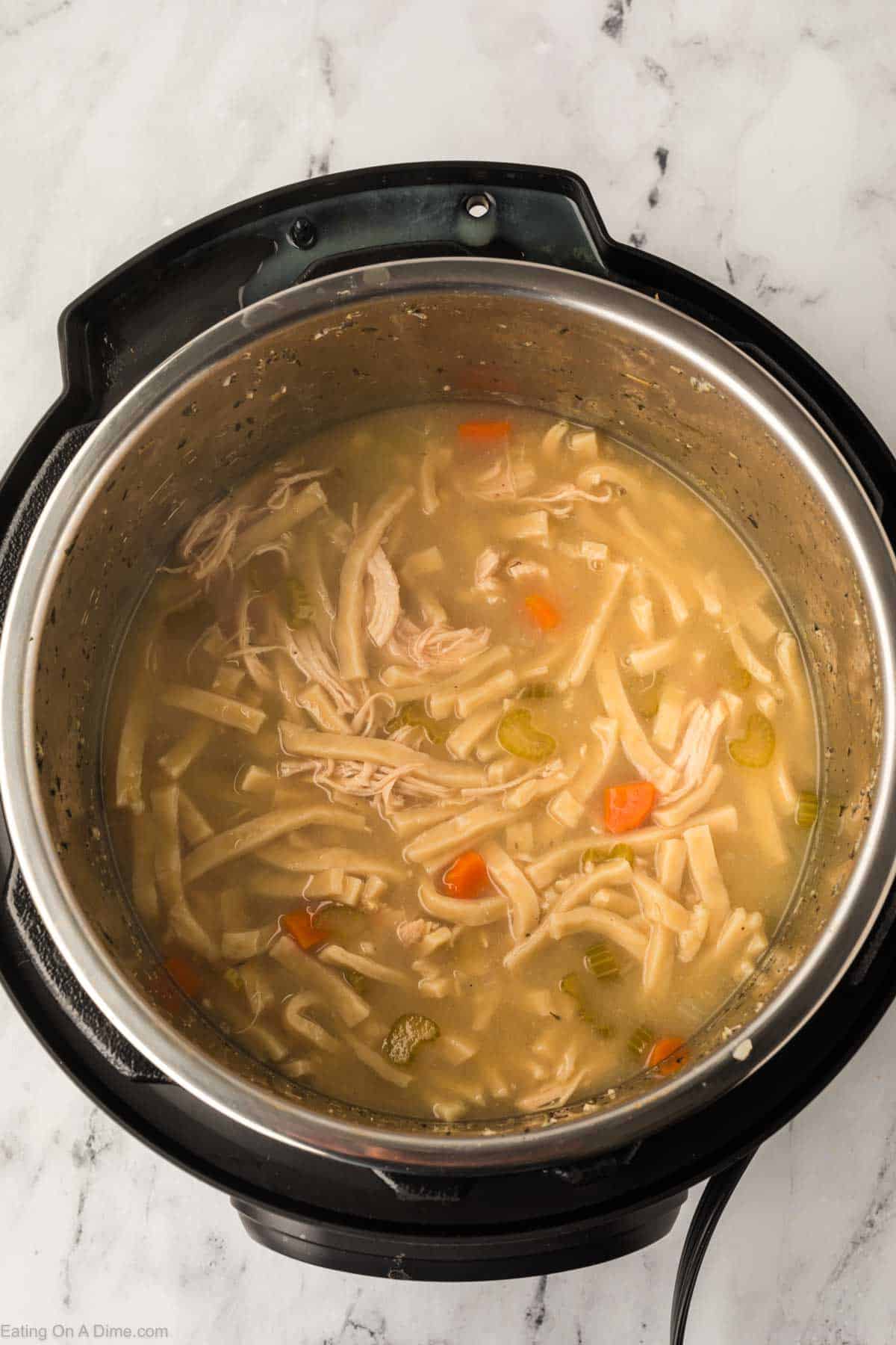 Noodles mixed with the chopped carrots and celery in broth with shredded chicken in the instant pot