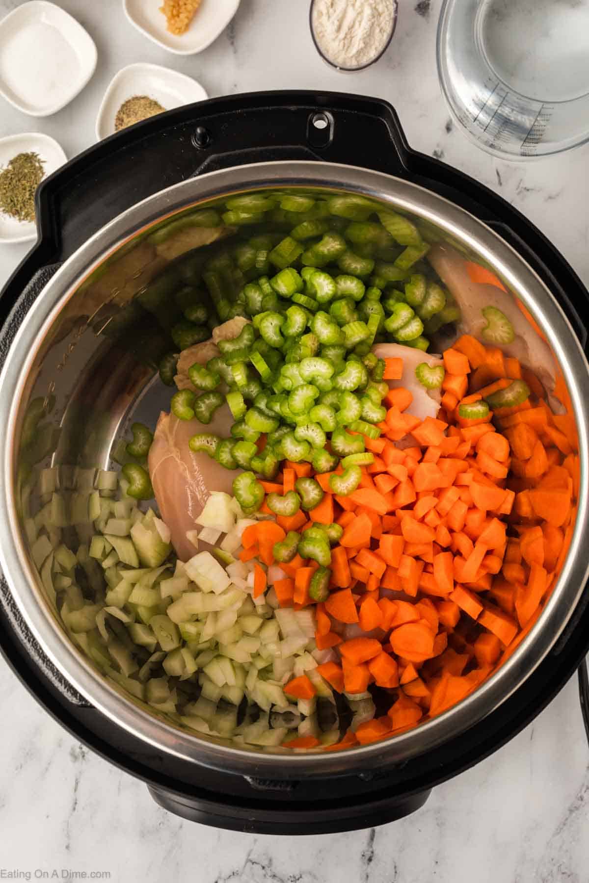 Chopped celery, carrots, onions and chicken breast in the instant pot