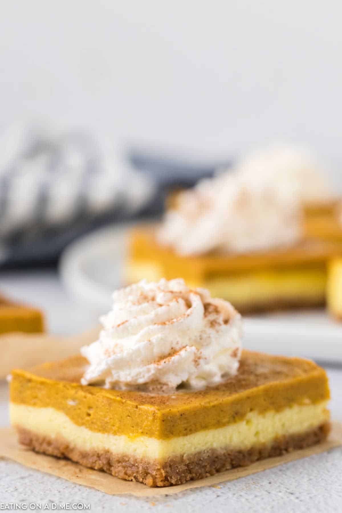 A slice of Pumpkin cheesecake bars topped with whipped cream