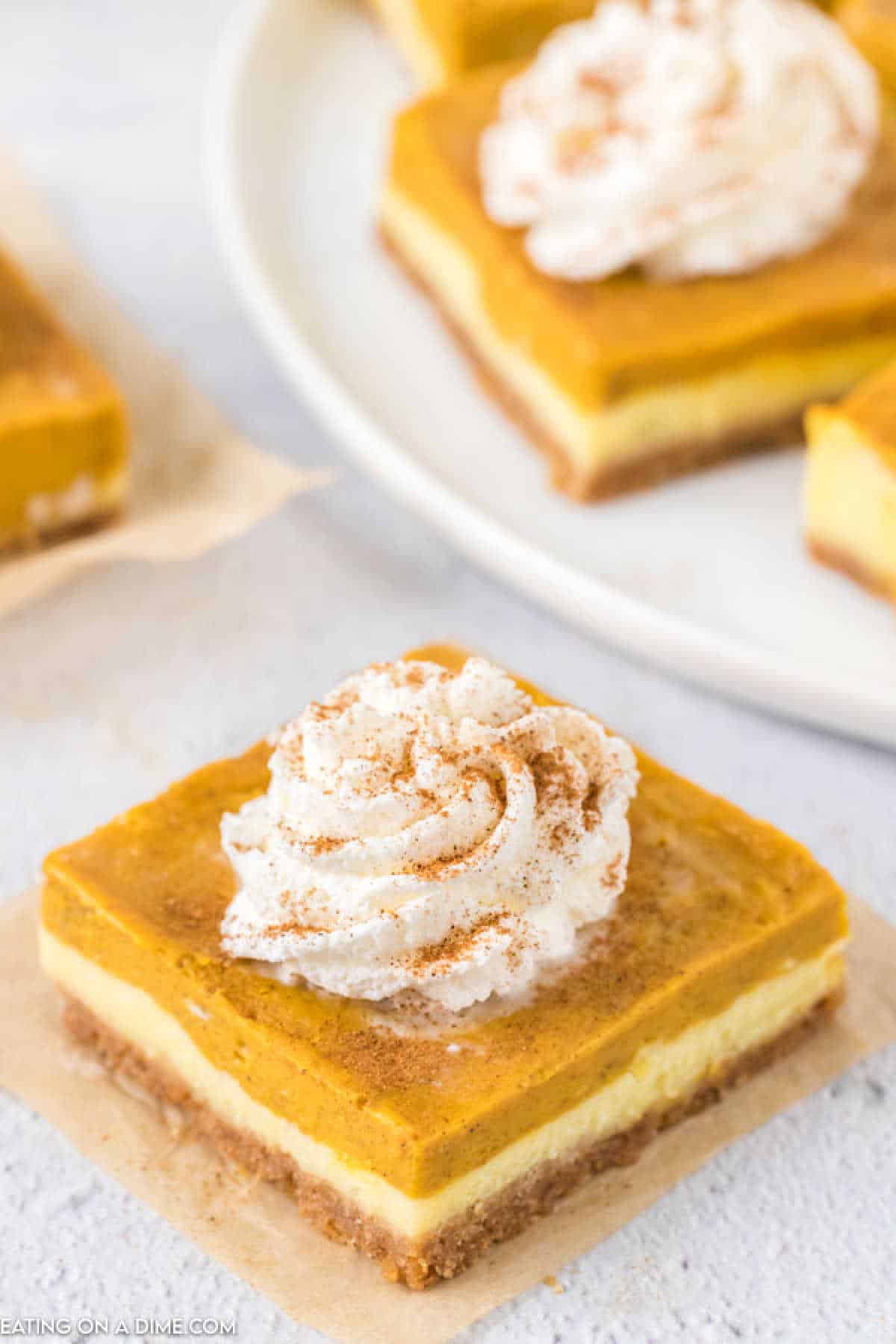 Slice pumpkin cheesecake bars topped with whipped cream