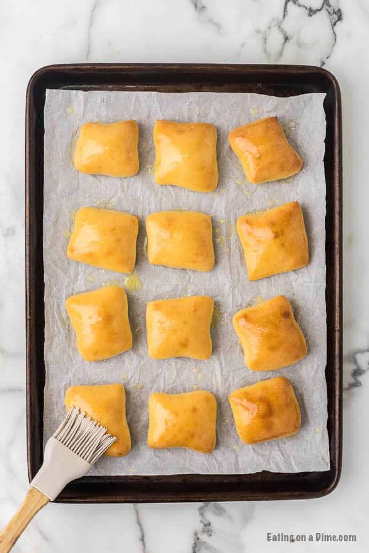 Baked rolls on a baking sheet brushed with melted butter