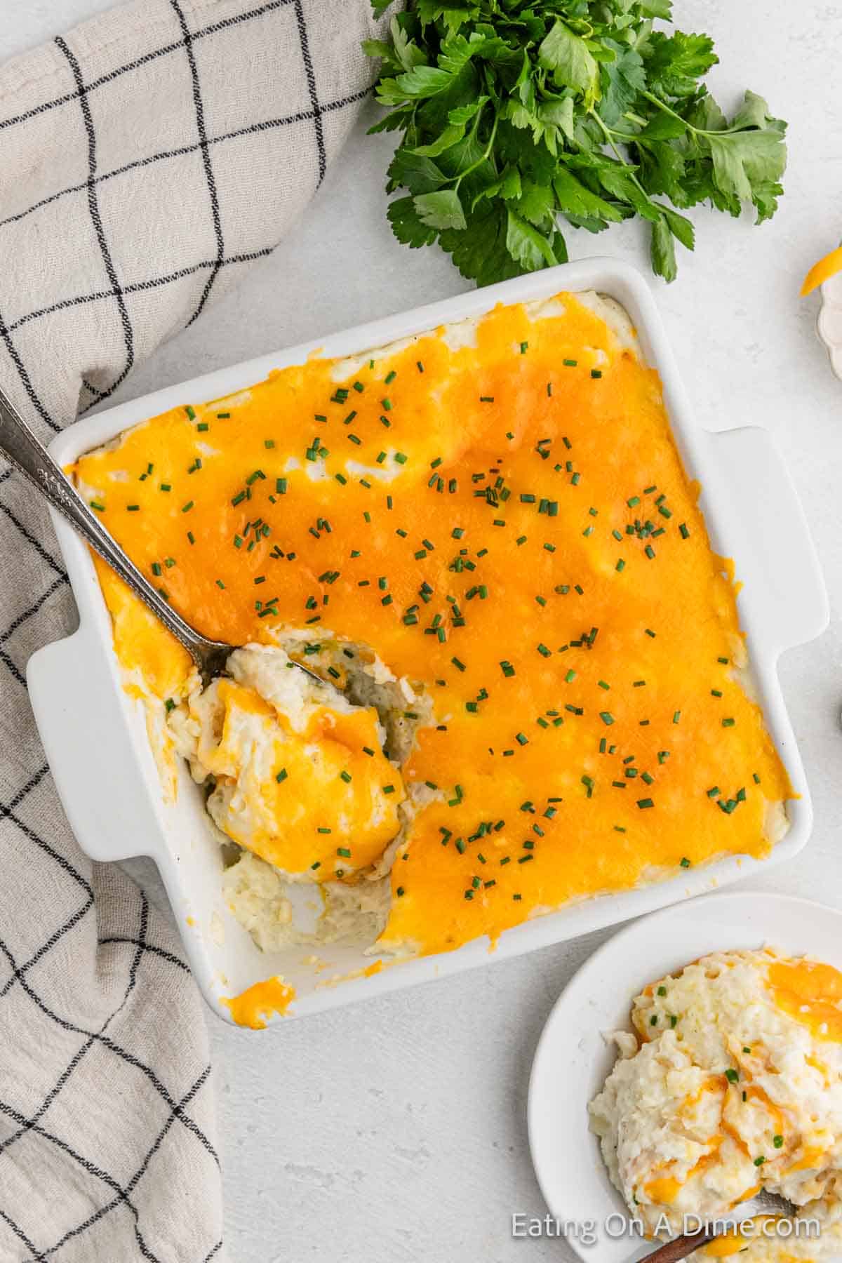 Cheesy potatoes in a casserole dish with a serving spoon