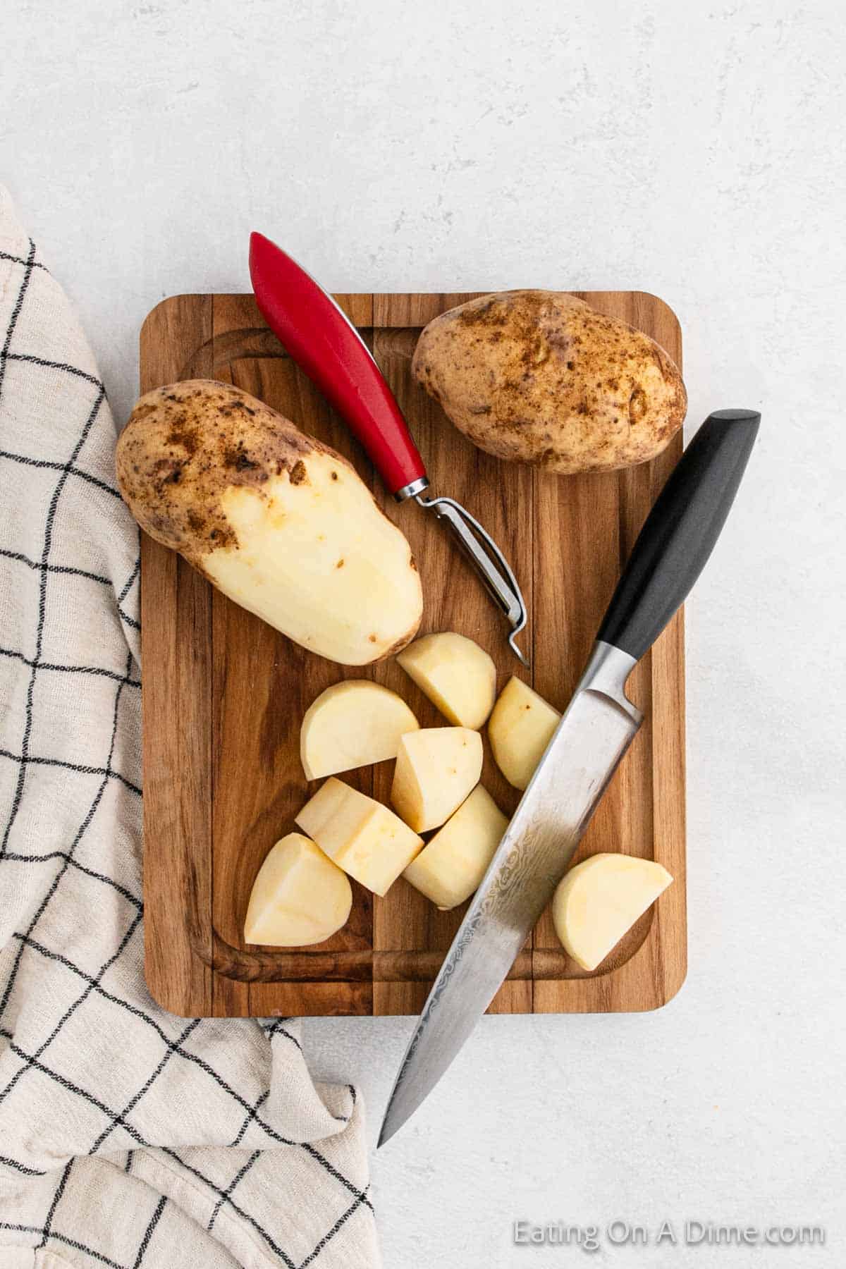 Peeling Russet Potatoes on a cutting board and then cutting potatoes into quarters