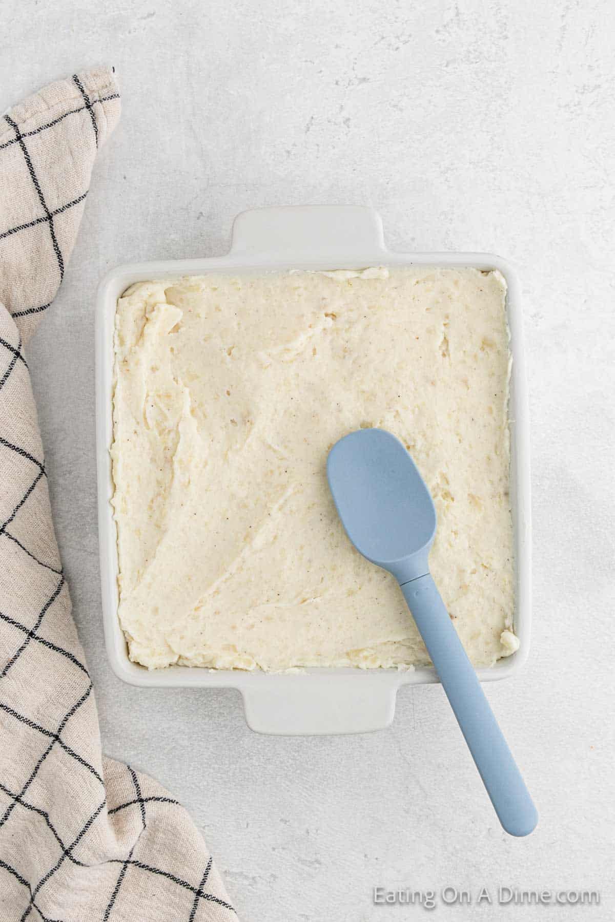 Spreading the mashed potatoes in a casserole dish with a spatula