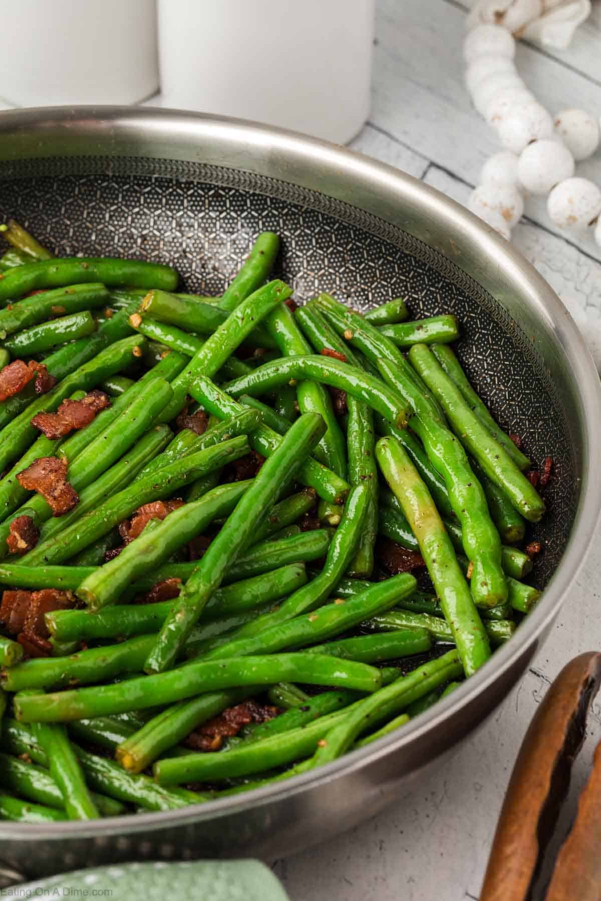 Fresh green beans trimmed and in a skillet with chopped bacon