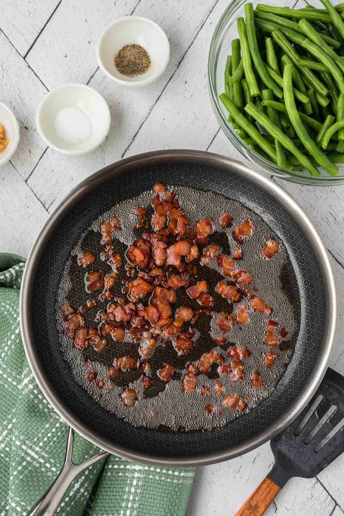 Cooked crispy bacon in a large skillet in bacon grease