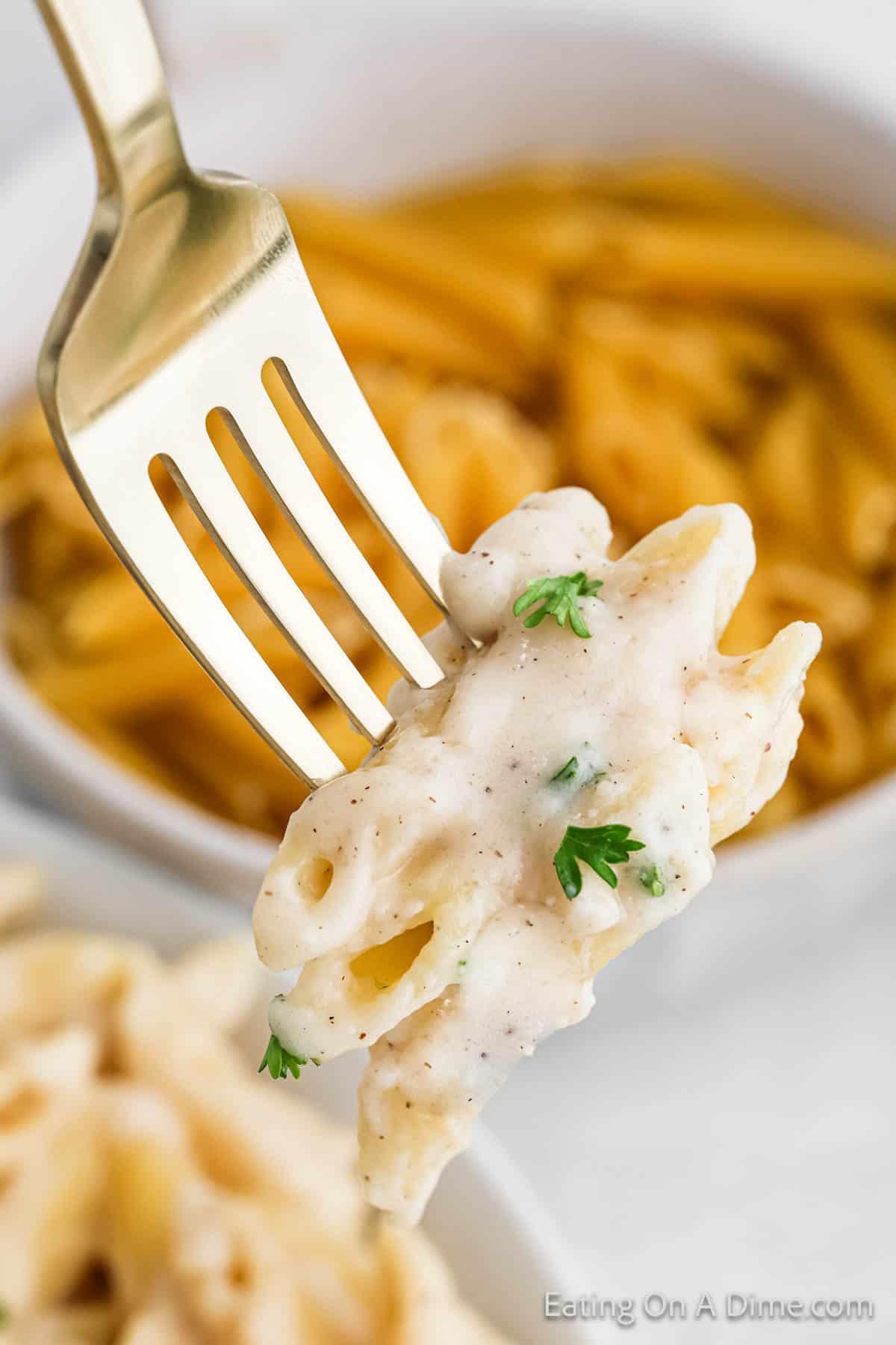 Penne Pasta mixed with a white sauce on a fork