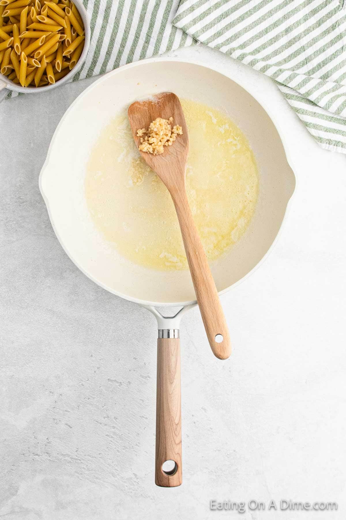 Melted butter in a skillet with minced garlic on the wooden spoon