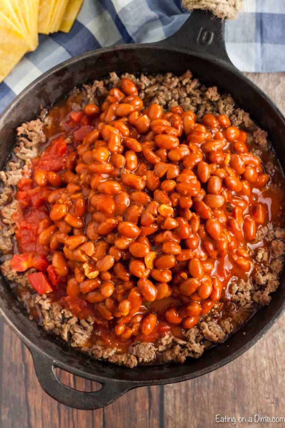 The meat mixture being cooked in a large cast iron pan. 