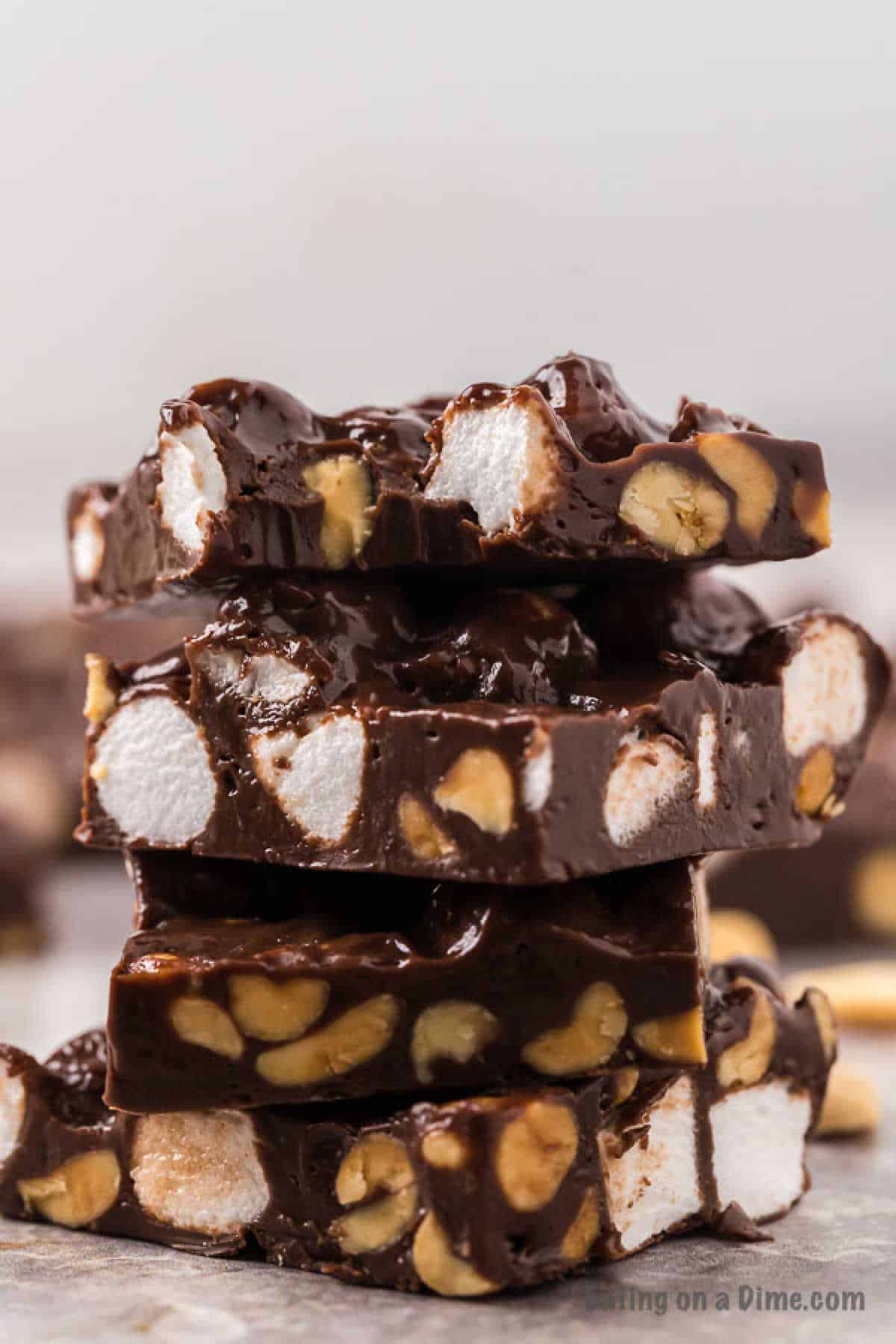 A stack of rocky road fudge pieces is shown with a close-up view, highlighting chunks of marshmallows and nuts embedded in rich, glossy chocolate. The background is blurred, making the fudge the clear focal point of the image—perfect for anyone seeking an easy rocky road fudge recipe.