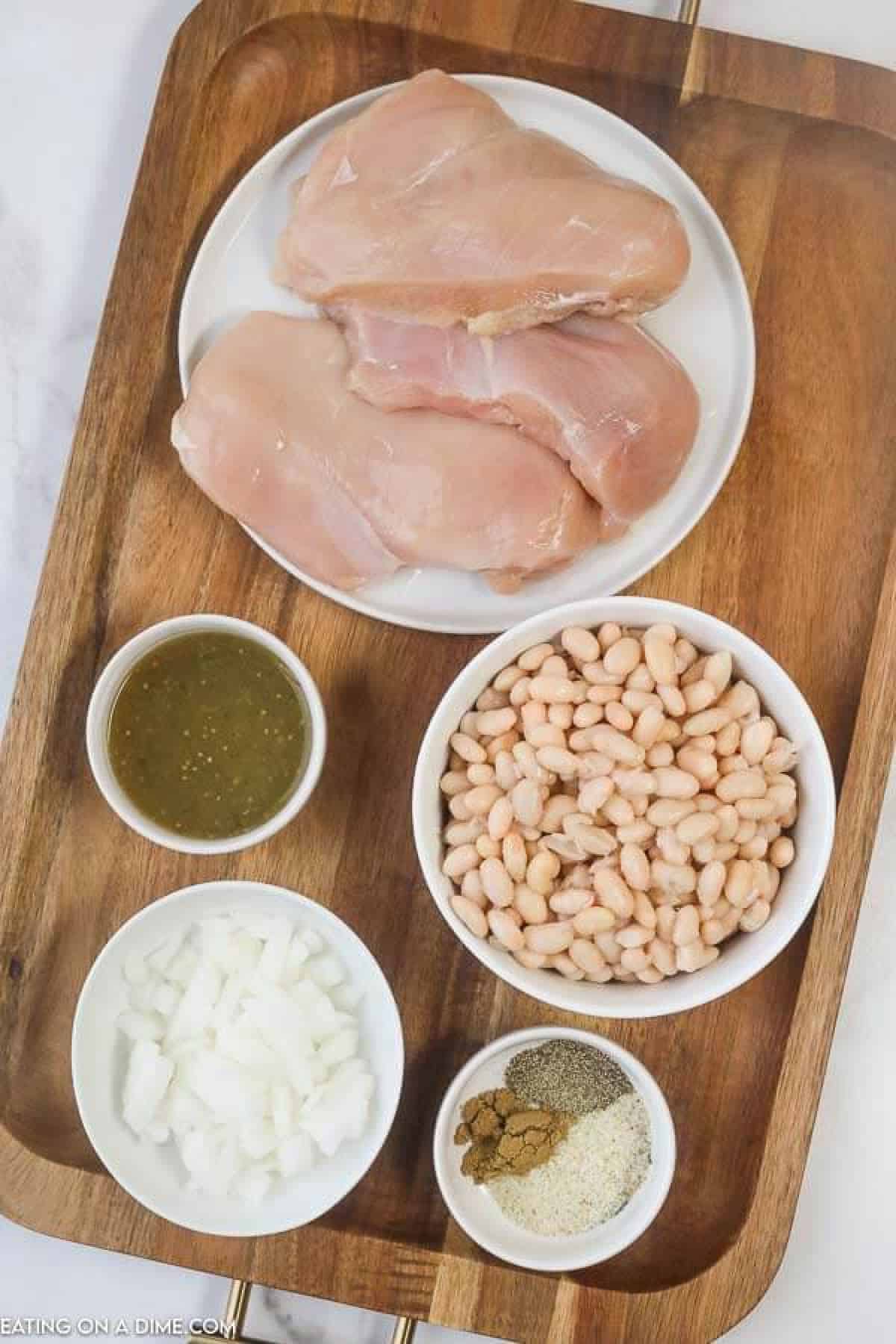 Close up image of chicken breast, white beans, onions, salsa verde, and ingredients on a serving tray. 