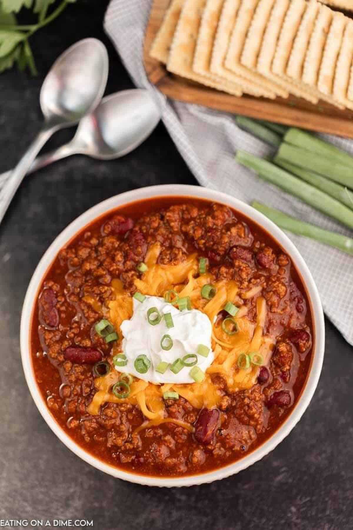 Bowl of chili topped with sour cream and cheese. 