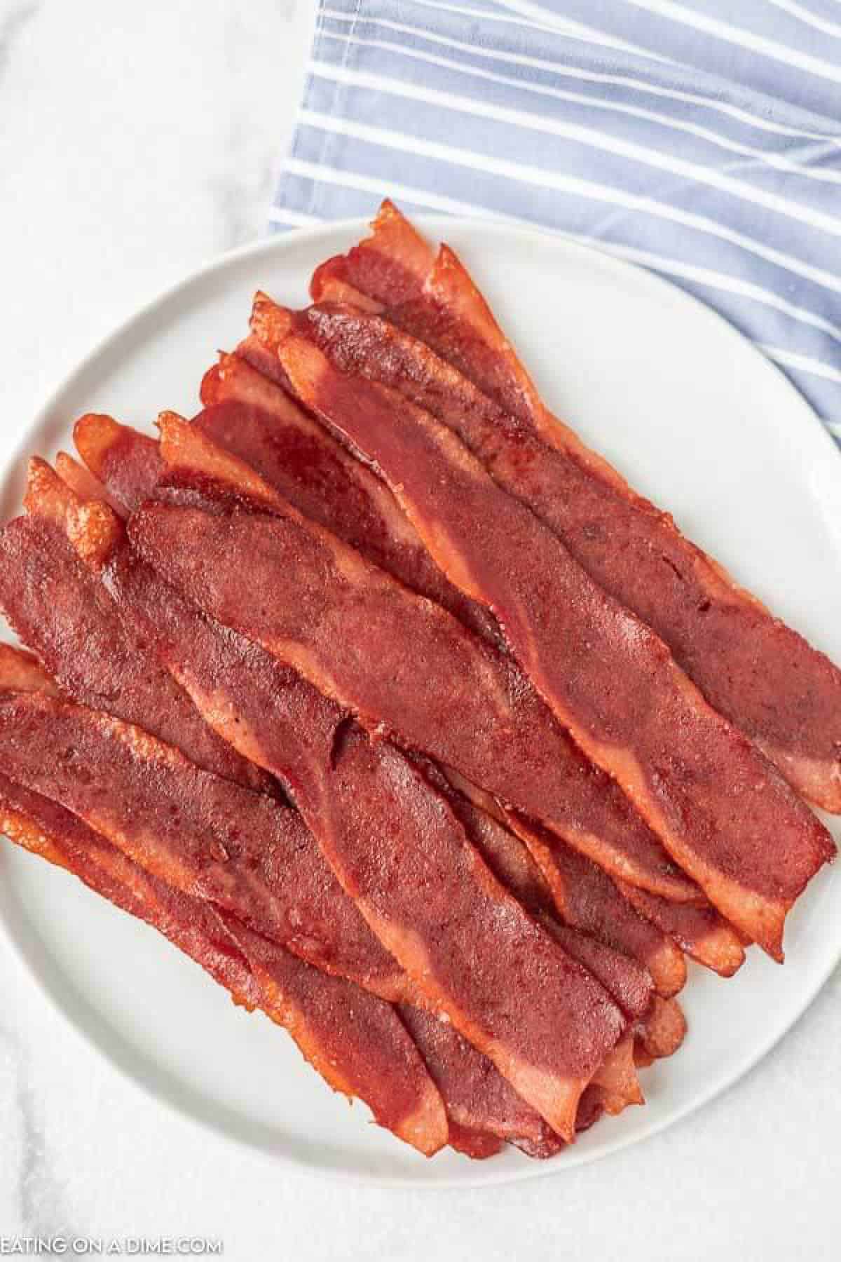 Close up image of cooked turkey bacon on a white plate. 
