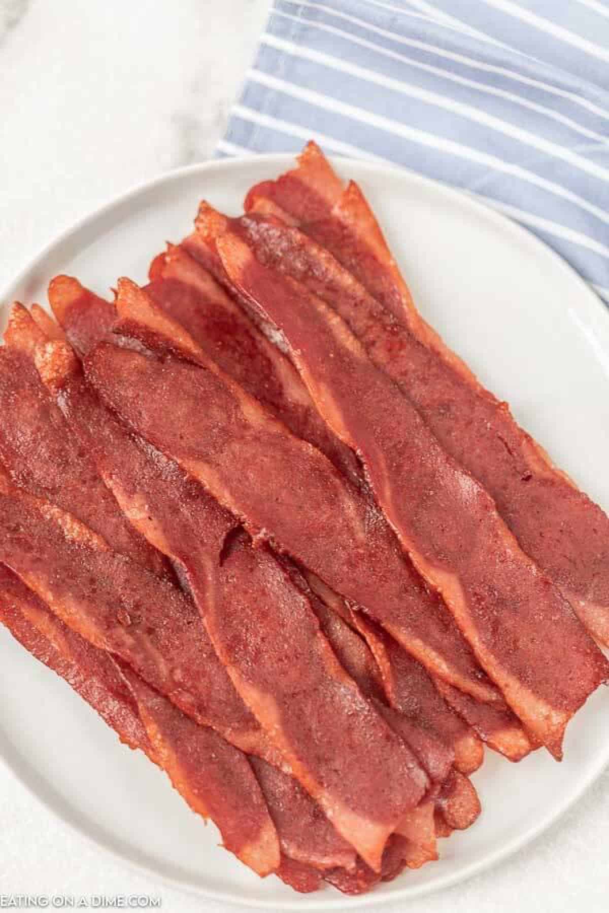 Close up image of cooked turkey bacon on a white plate. 