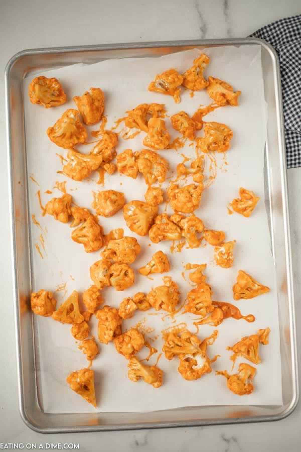 Close up image of buffalo cauliflower on a cookie sheet lined with parchment paper. 