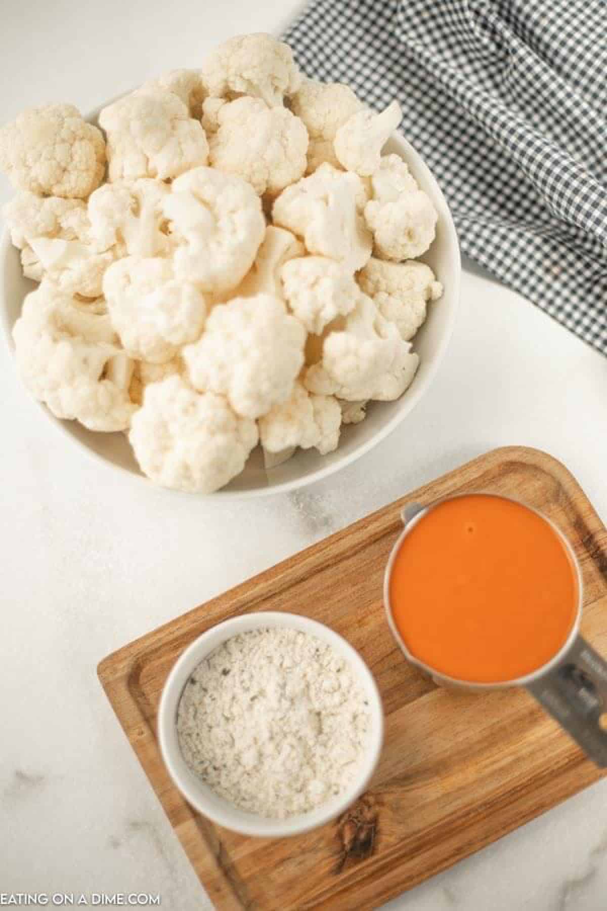 Close up image ingredients needed for buffalo cauliflower - cauliflower, buffalo sauce and ranch seasoning mix. 