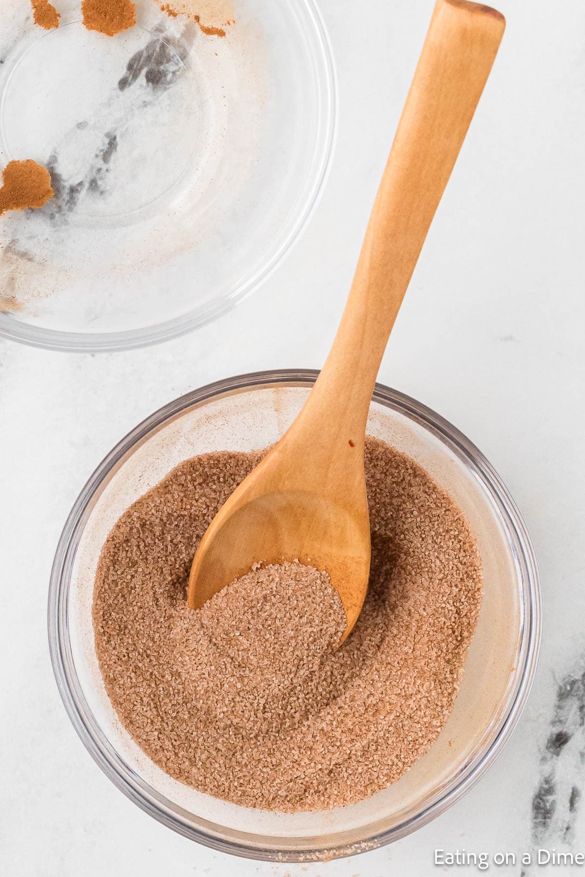 Combining sugar and cinnamon in a bowl with a wooden spoon