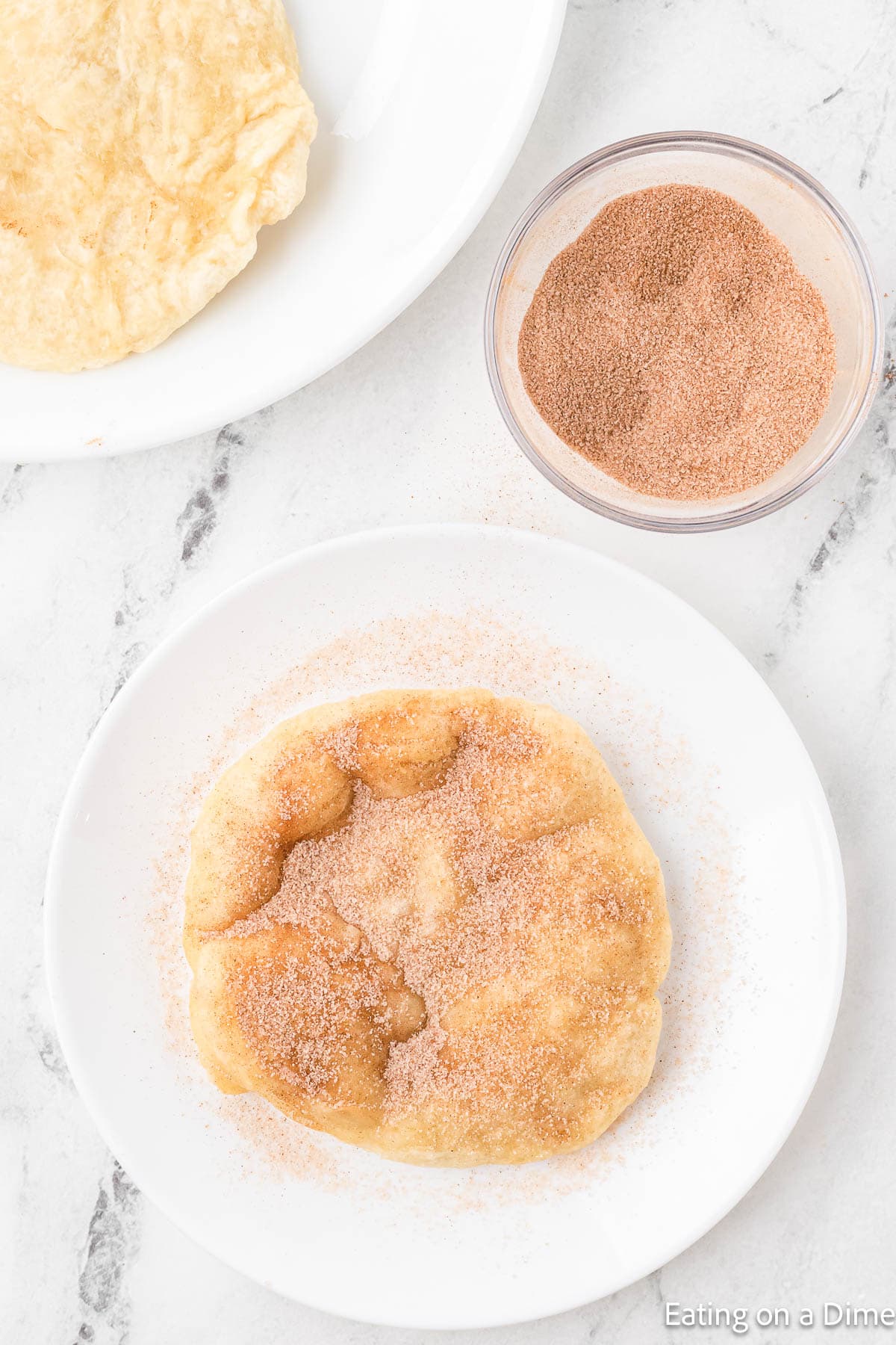 Cinnamon and sugar mixture sprinkled over fry bread on a plate